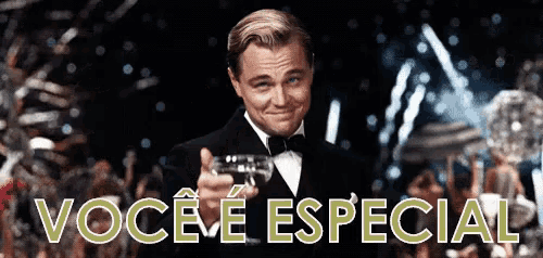 a man in a tuxedo is holding a glass of wine in front of a sign that says você e especial