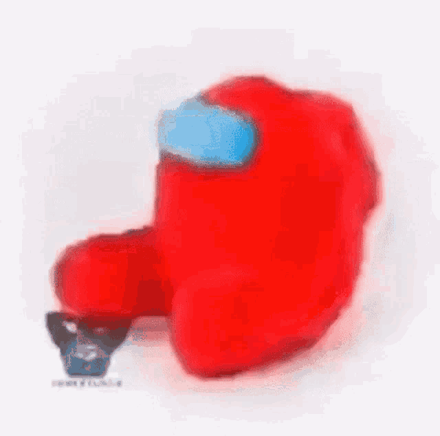 a red among us stuffed animal with a blue mask on its face is sitting on a white surface .