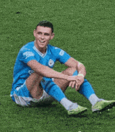 a soccer player is sitting on the grass with his legs crossed