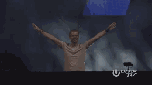 a man in a grey shirt is dancing on a stage in front of a sign that says umf tv .
