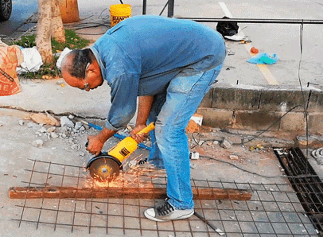 a man is using a grinder to cut a piece of metal on the ground