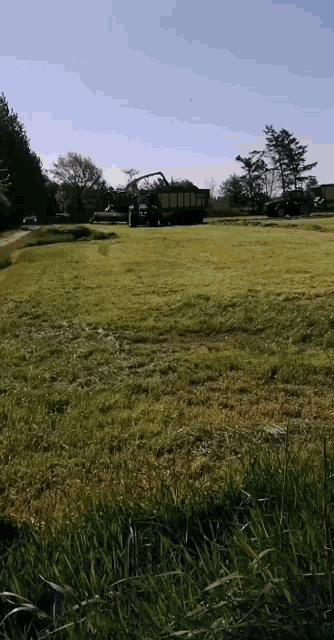 a truck is loading hay into a trailer in a grassy field