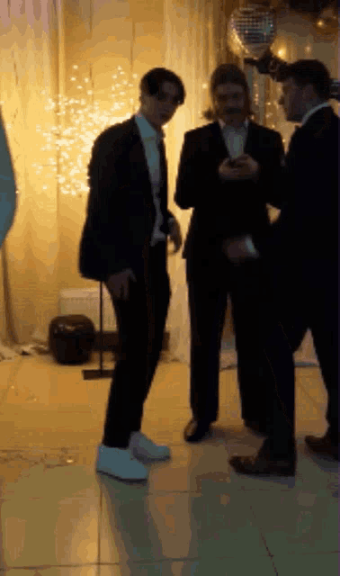 a group of men are standing in a room with a disco ball