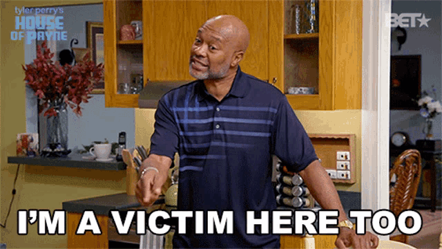 a man is standing in a kitchen with the words i 'm a victim here too