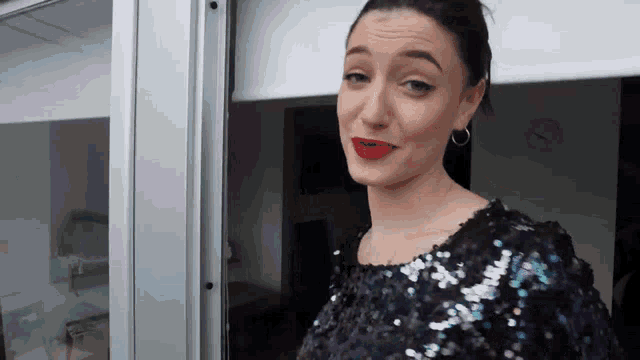 a woman in a sequined top stands in front of a glass door