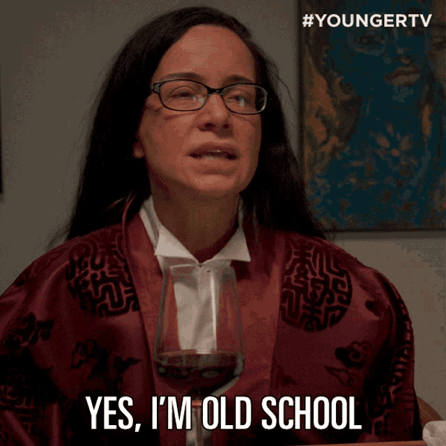 a woman is holding a glass of wine and saying yes i 'm old school