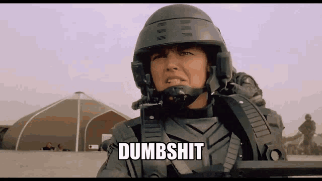 a woman in a helmet is holding a gun and the word dumbshit is above her