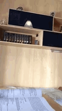 a shelf with a lot of books on it and papers on the floor