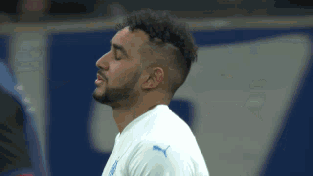 a man with a beard wears a white shirt with the puma logo on the sleeve