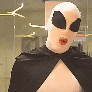 a person with a mask on their face and a black cape on