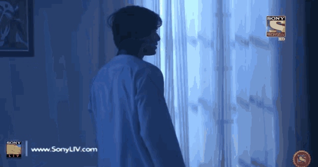 a man stands in front of a window with a sony logo on the bottom right