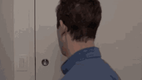 a man in a blue shirt is opening a door in a room .