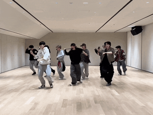 a group of young men are dancing in a room with a large mirror