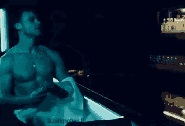 a shirtless man is sitting at a bar with a towel around his waist