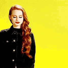 a woman with red hair is wearing a black jacket and red lipstick .
