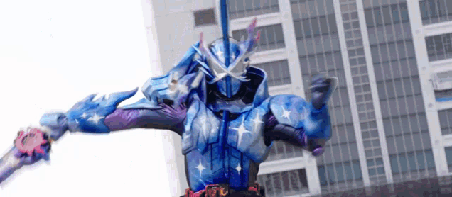 a person in a blue and purple costume is holding a sword in front of a tall building .