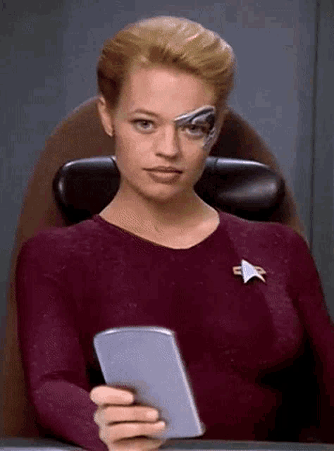 a woman with a robotic eye is holding a cell phone in her hand