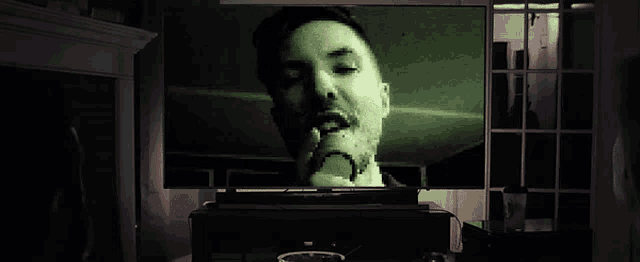 a man is smoking a cigarette in front of a television
