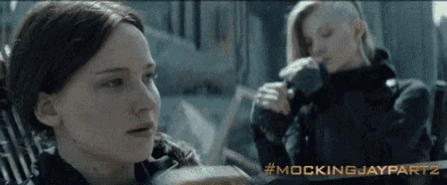two women are sitting next to each other with the words mockingjaypartz written on the bottom