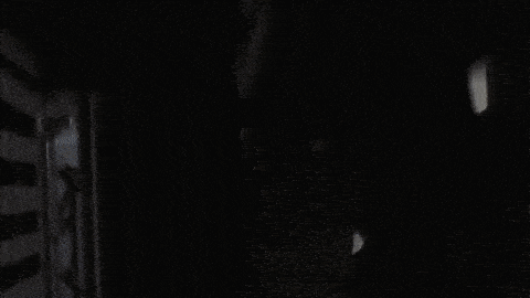 a person is standing in a dark room with a striped wall behind them