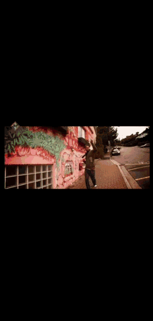 a man walking down a sidewalk in front of a colorful wall