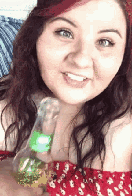 a woman holding a bottle with a green label that says ' coca cola ' on it