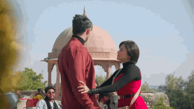 a man and a woman dancing in front of a gazebo