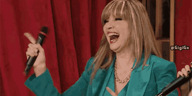 a woman in a blue jacket is singing into a microphone while laughing .