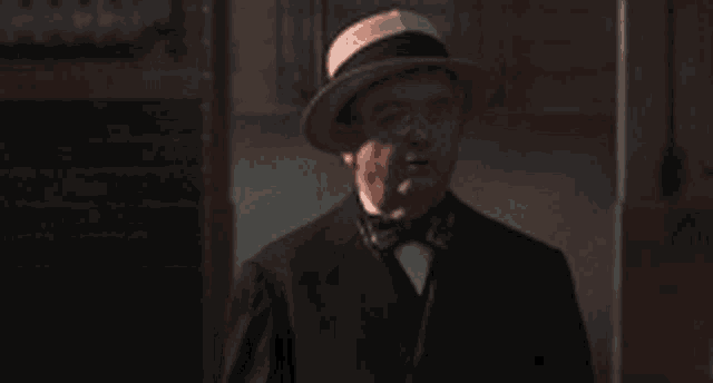 a man in a suit and hat is standing in a dark room