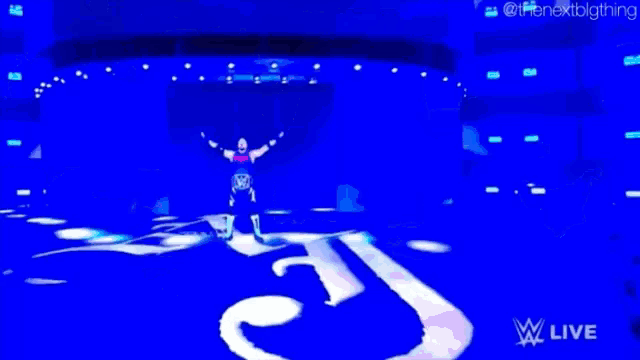 a man is standing on a stage with his arms in the air and the words wwe live on the bottom