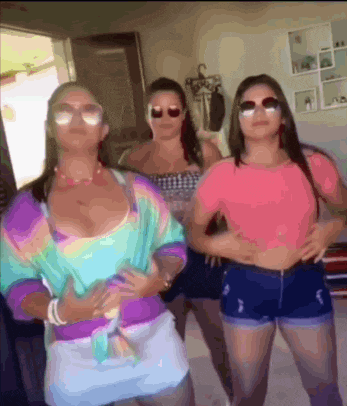 three women wearing sunglasses and shorts are standing next to each other .