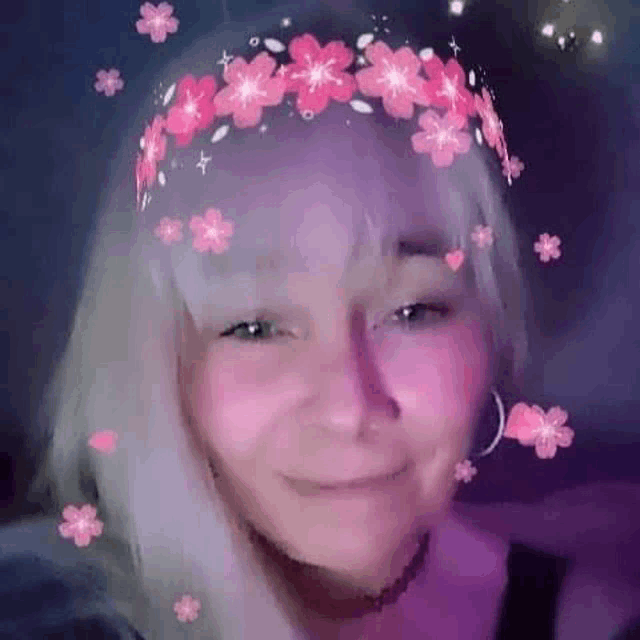 a woman wearing a flower crown on her head is smiling and looking at the camera .