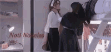 two women standing in front of a sign that says noti novelas on it