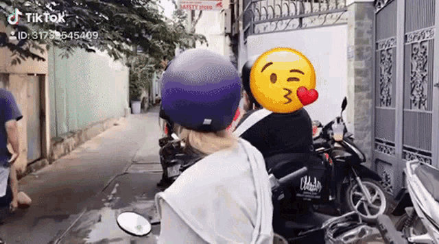 a person is riding a motorcycle with a smiley face on their head .