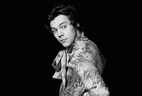 a black and white photo of a young man wearing a floral shirt and tie .