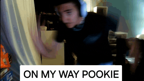 a man wearing headphones stands in front of a white sign that says on my way pookie