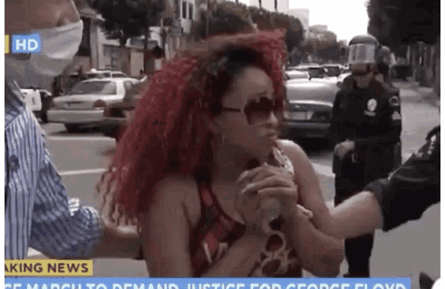 a woman with red hair is being arrested by a police officer on a news channel