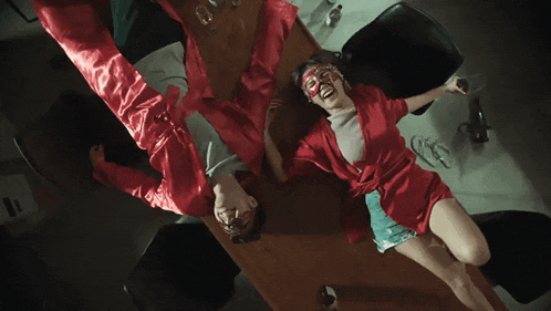 a woman in a red robe is laying on a table with a man in a red robe