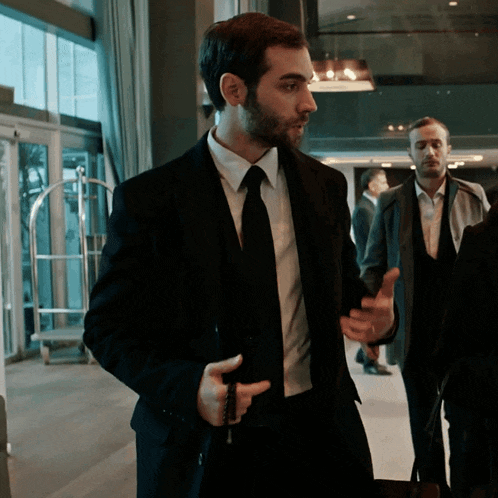 a man in a suit and tie holds a suitcase