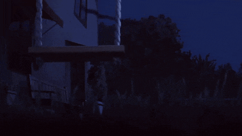 a dark scene with a house and trees in the background
