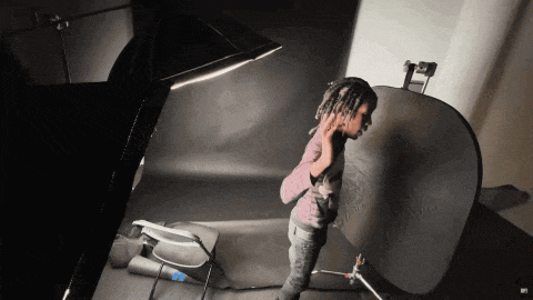 a person with dreadlocks is standing in a dark room with a black background