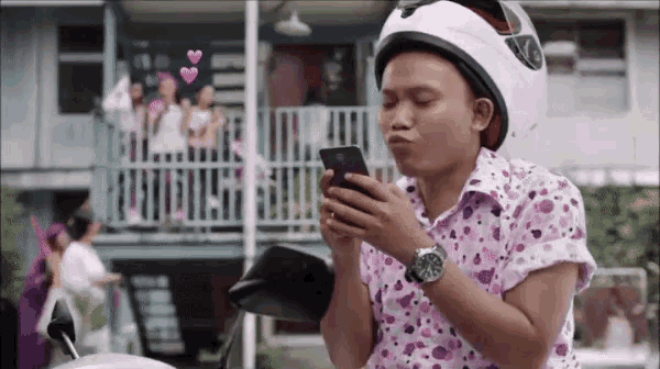 a man wearing a helmet is using a cell phone .