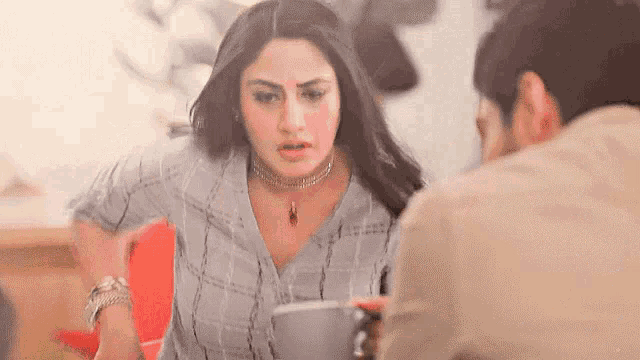 a woman is sitting at a table with a cup of coffee and a man .