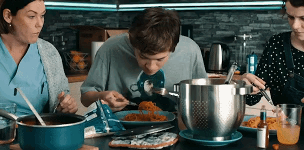 a boy is eating spaghetti while two women watch