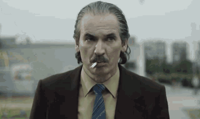 a man in a suit and tie is smoking a cigarette in his mouth .
