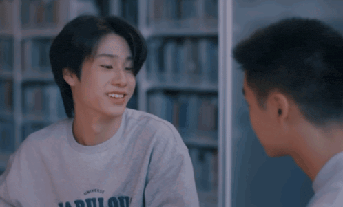 a young man wearing a converse sweatshirt talks to another young man