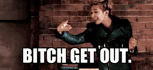 a man in a green jacket is dancing in front of a brick wall with the words " bitch get out " above him