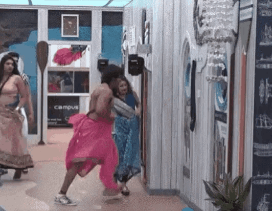 a man in a pink skirt is running through a hallway
