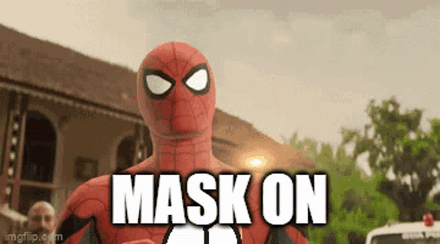 a man in a spiderman costume says mask on in front of a building