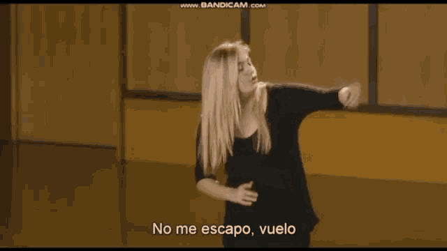 a woman in a black shirt is dancing and says no me escapo vuelo in spanish